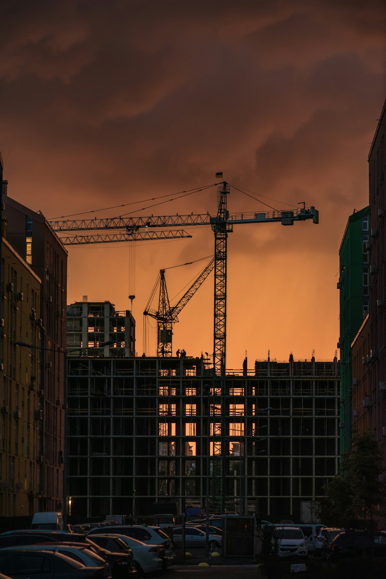 Industrial construction crane and building silhouettes over sun at sunset